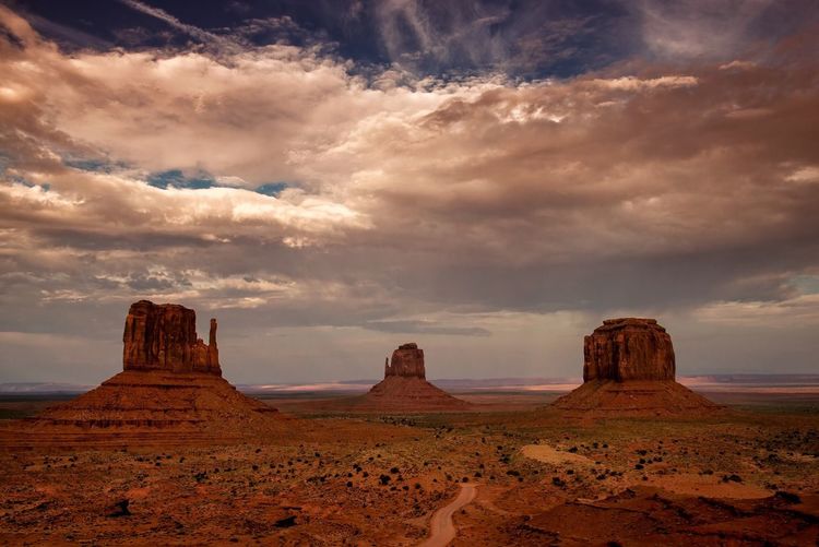 View of rock formations in desert against cloudy sky