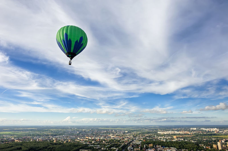 Hot air balloon flying over city against sky