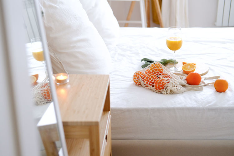 Oranges and orange juice in a glass on a white bed