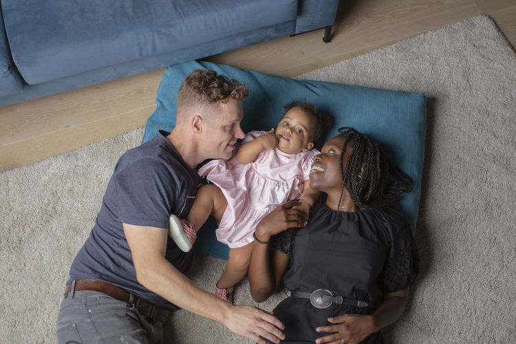 A biracial family laying on the floor with their daighter