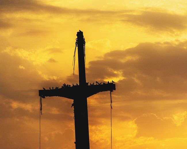 Low angle view of silhouette cross against sky during sunset
