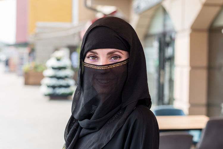 Young beautiful slender muslim woman walks through the street shops. person