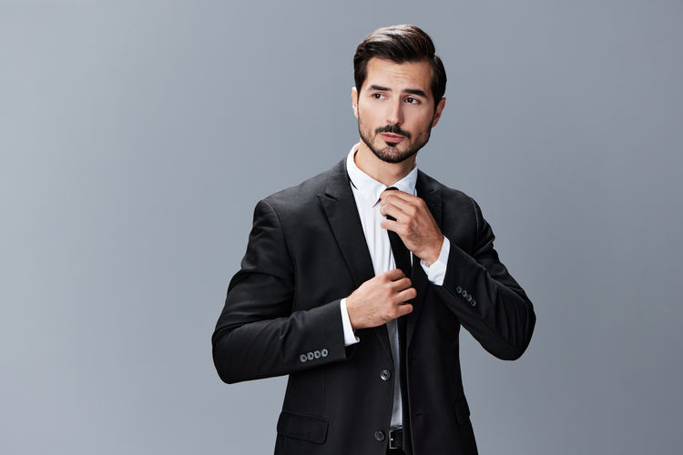 Portrait of businessman standing against gray background