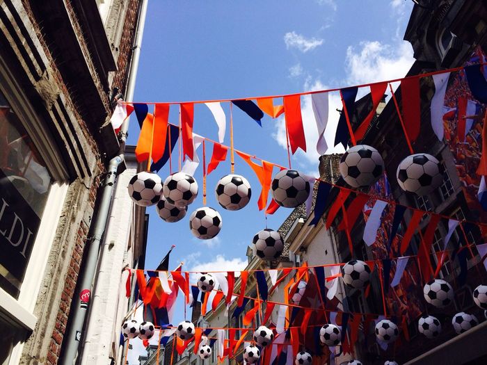 Low angle view of soccer balls hanging from rope against sky