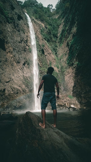 Rear view of woman standing against waterfall