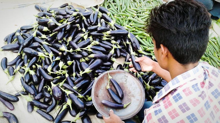 High angle view of man picking eggplants at market