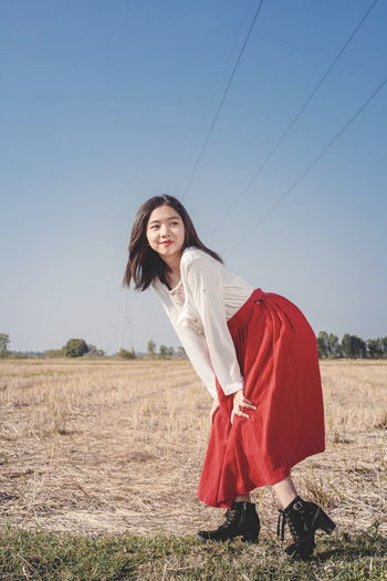 Young woman standing on field against clear sky