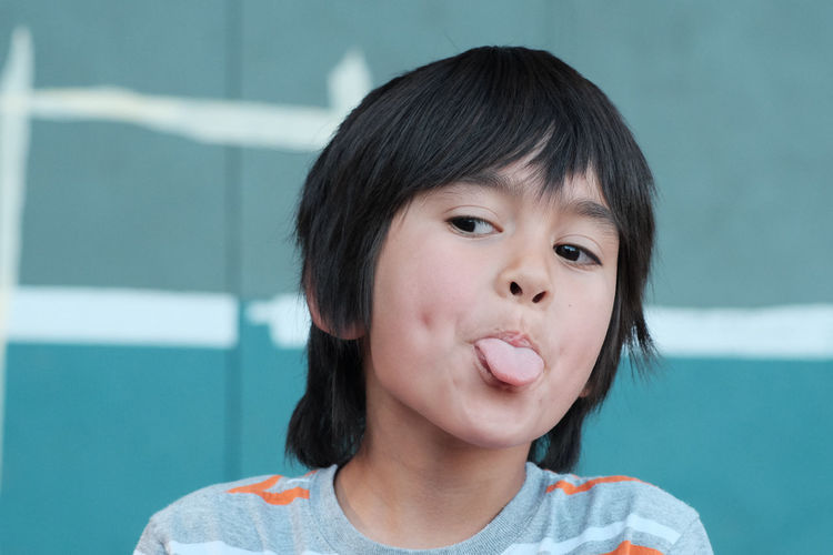 Close-up of boy sticking out tongue while looking away