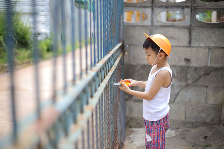 Side view of boy cutting fence