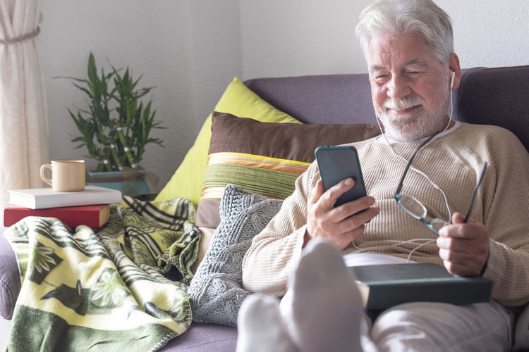 Midsection of man using mobile phone while sitting on sofa at home