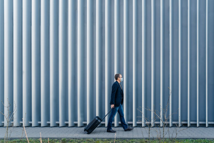Side view of man carrying suitcase on footpath