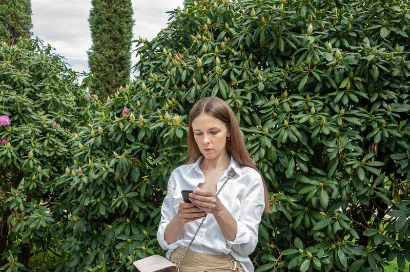 Young woman looking away while plants outdoors
