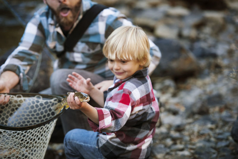 Boy holding fish while standing by father