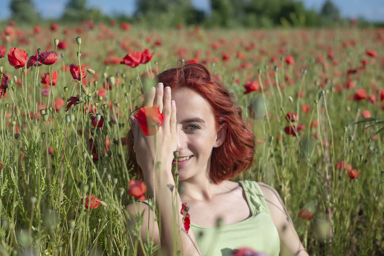 Portrait of young woman with flowers blooming on field