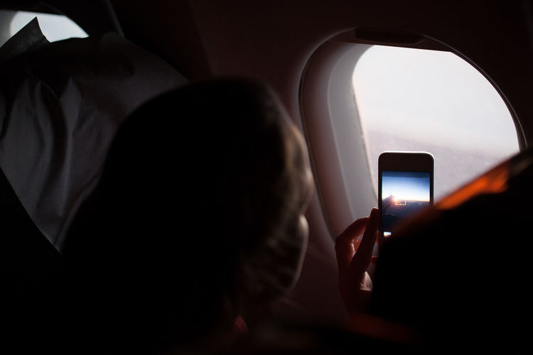 Close-up of woman photographing through airplane window