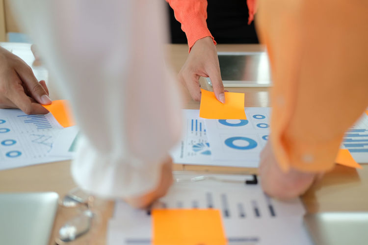 Cropped image of business person holding adhesive notes on table at office