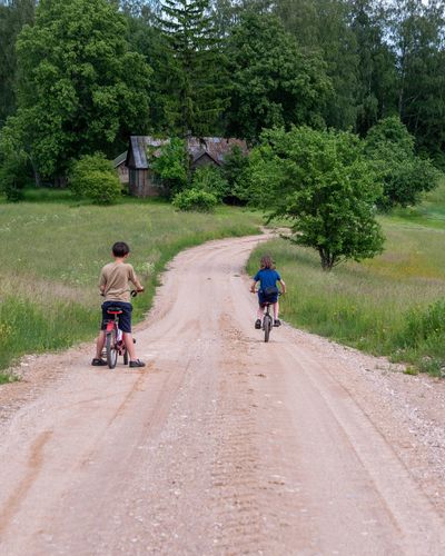 Rear view of two children riding bicycle on a country road