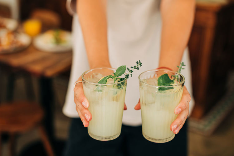 Woman holding non-alcoholic beverage, cold lemonade with mint and ice