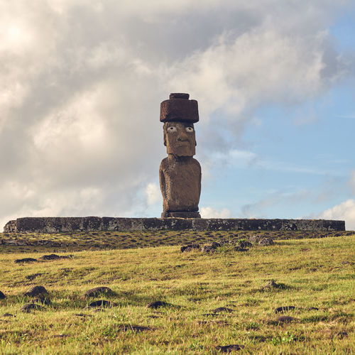 Stack of moai statues on field against sky