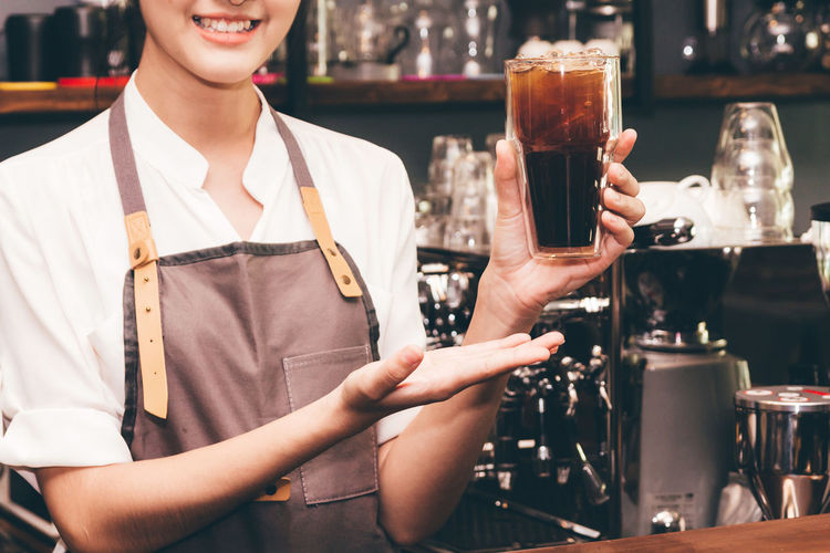 Midsection of barista holding coffee at cafe