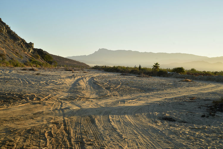 Scenic view of sandy beach and mountains against clear sky