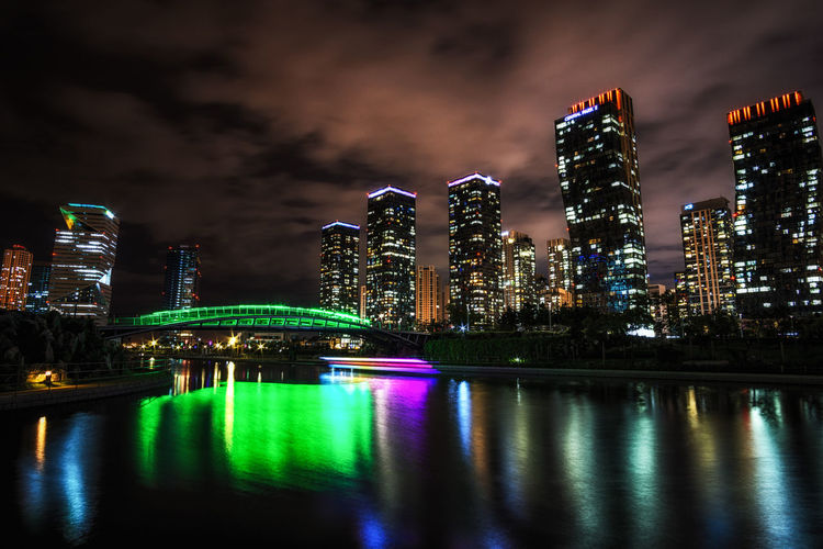 Illuminated buildings by river at night