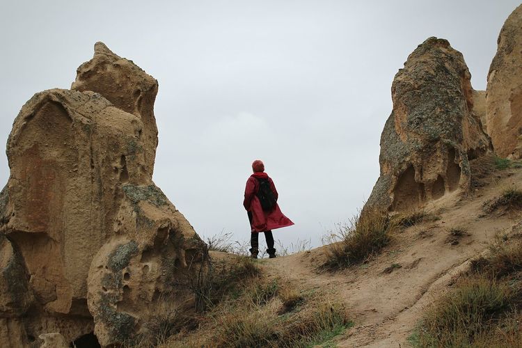 Rear view of hiker amidst rock formation against sky at cappadocia