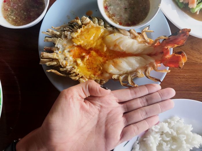Cropped hand gesturing by seafood on table