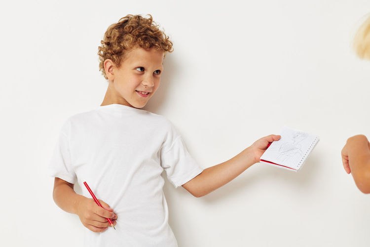 Smiling boy holding notebook against white background