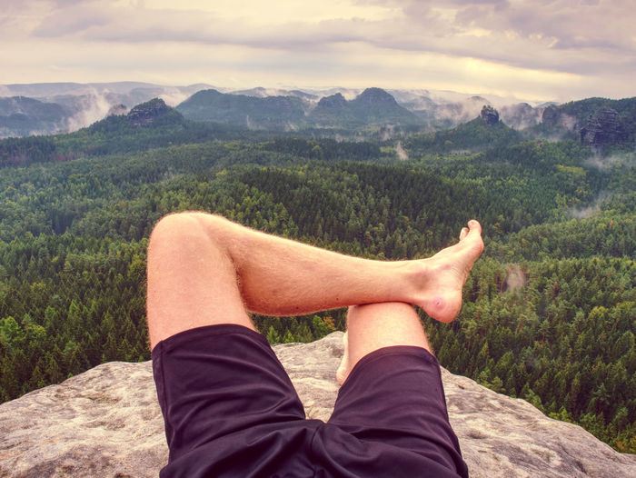 Big bloody callus on man's heel. male feet relax on rocky summit at edge. man enjoy adventure