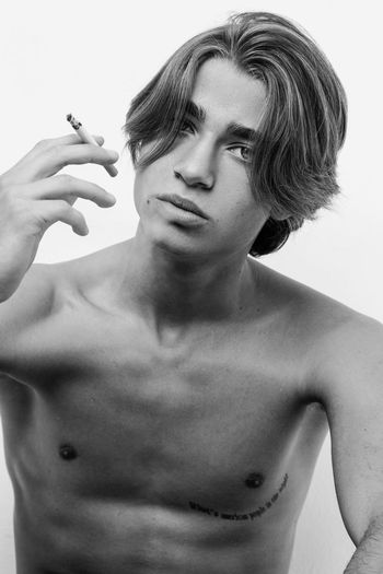 Portrait of shirtless man smoking against white background