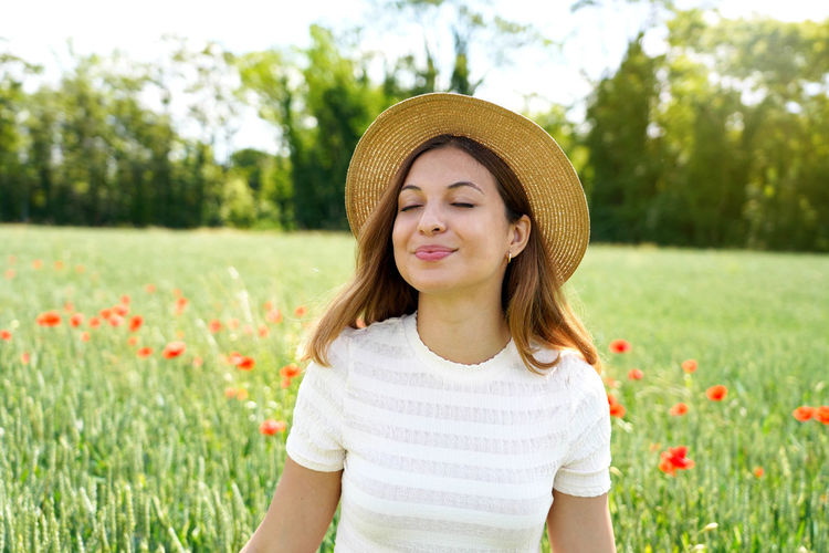 Close-up of smiling woman face wearing hat on field