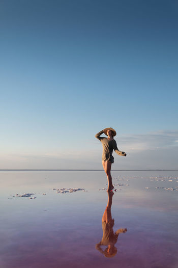 Evening view of the shallow salty pink lake. reflection. a young woman in a hat walks on the water 