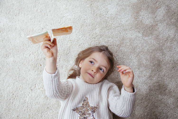 High angle portrait of girl playing with paper airplane 