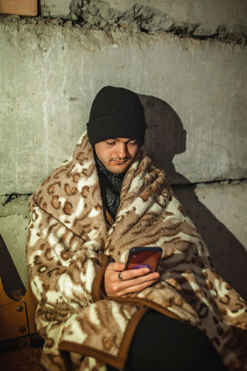 Ukrainian young man sits in bomb shelter and reads latest braking news about russian invaders