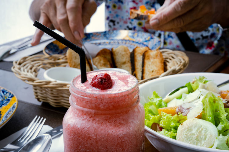 Strawberry shake, vegetable salad and bread on the table.
