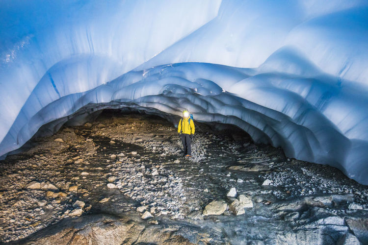 Explorer standing under glacier in cave.