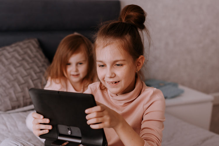 Smiling young woman using laptop while sitting on sofa at home