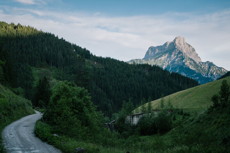 Scenic view of road by mountains against sky