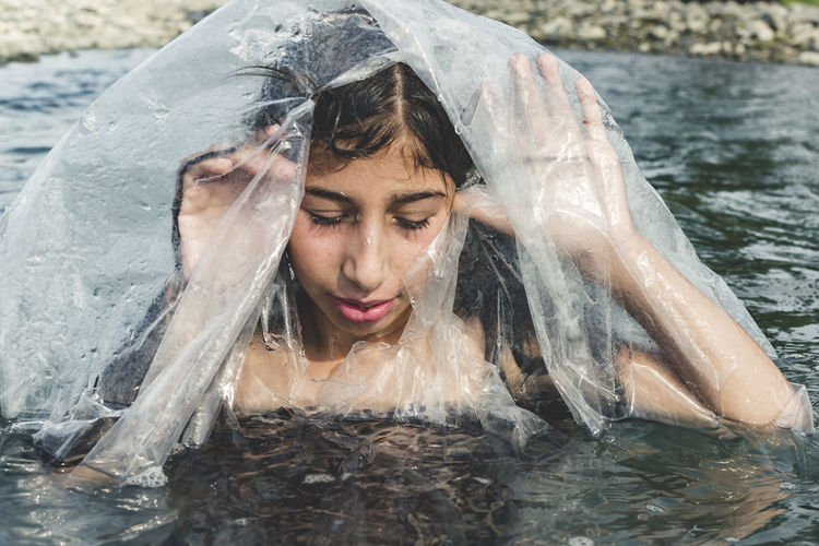Close-up of girl amidst plastic in sea