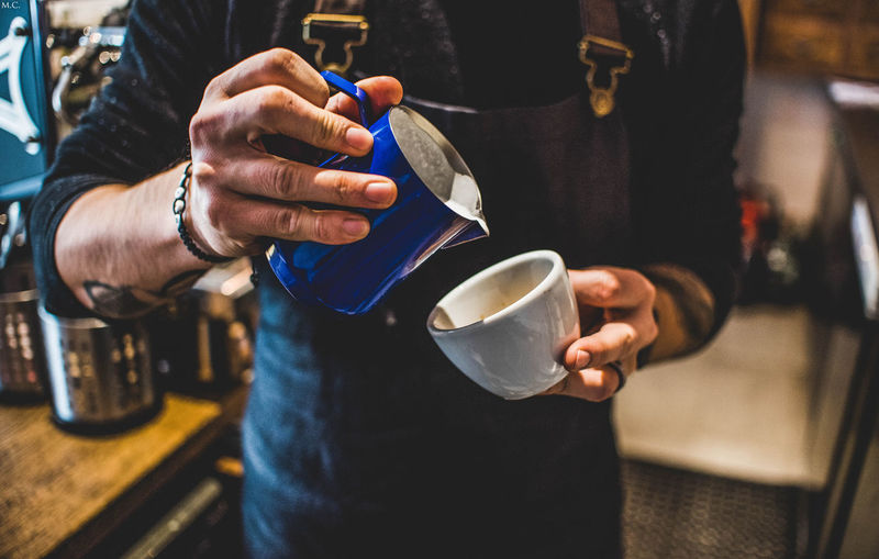 Midsection of man holding coffee cup at cafe