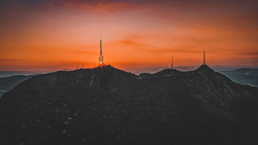 Silhouette tower on landscape against sky during sunset