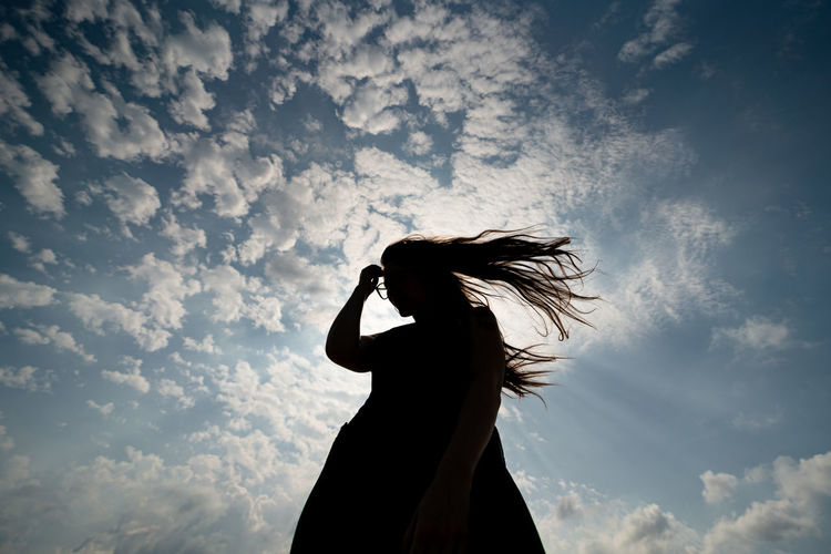 Low angle view of silhouette woman standing against sky