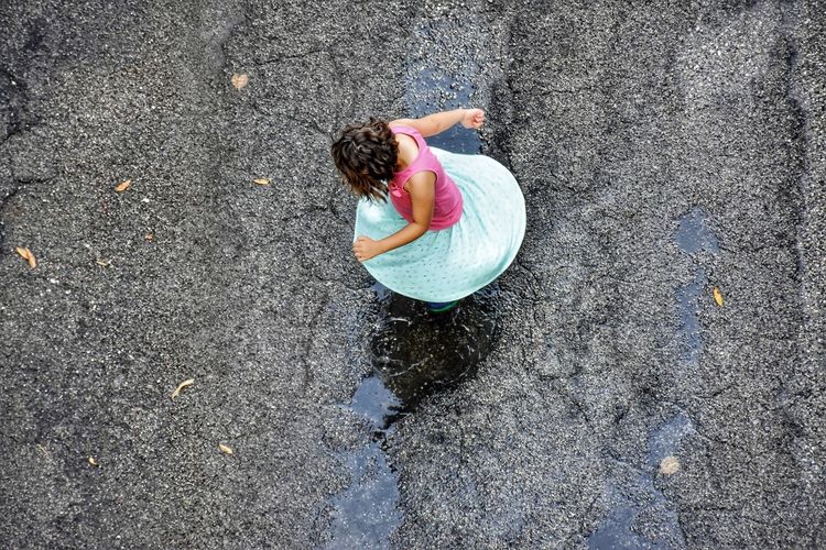 High angle view of girl playing on puddle at road