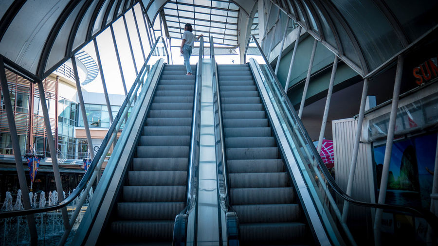 Low angle view of mid adult woman standing on escalator