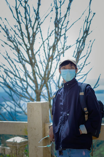 Rear view of man standing against bare tree