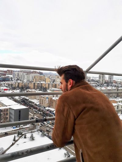Man looking at cityscape against sky