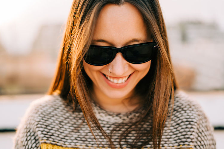 Close-up of smiling woman wearing sunglasses looking down