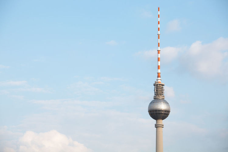 Low angle view of fernsehturm against cloudy sky