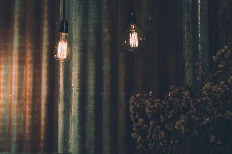 Illuminated light bulbs hanging against wall